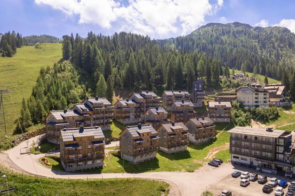 Luftaufnahme des Nassfeld Almresorts mit mehreren Chalet-Gebäuden im Alpenpanorama