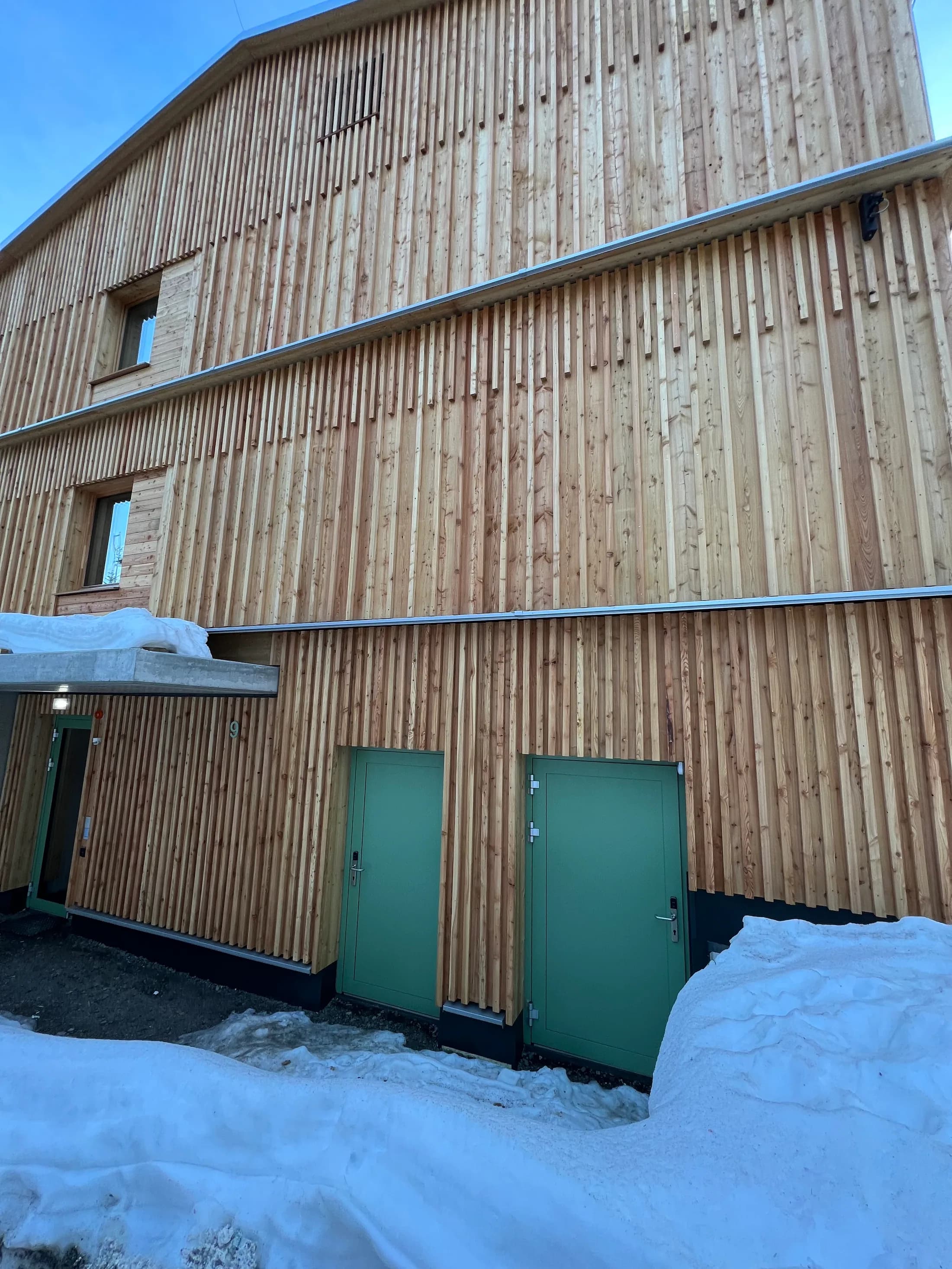 Zwei grüne Türen in einer Holzfassade, fachgerecht montiert