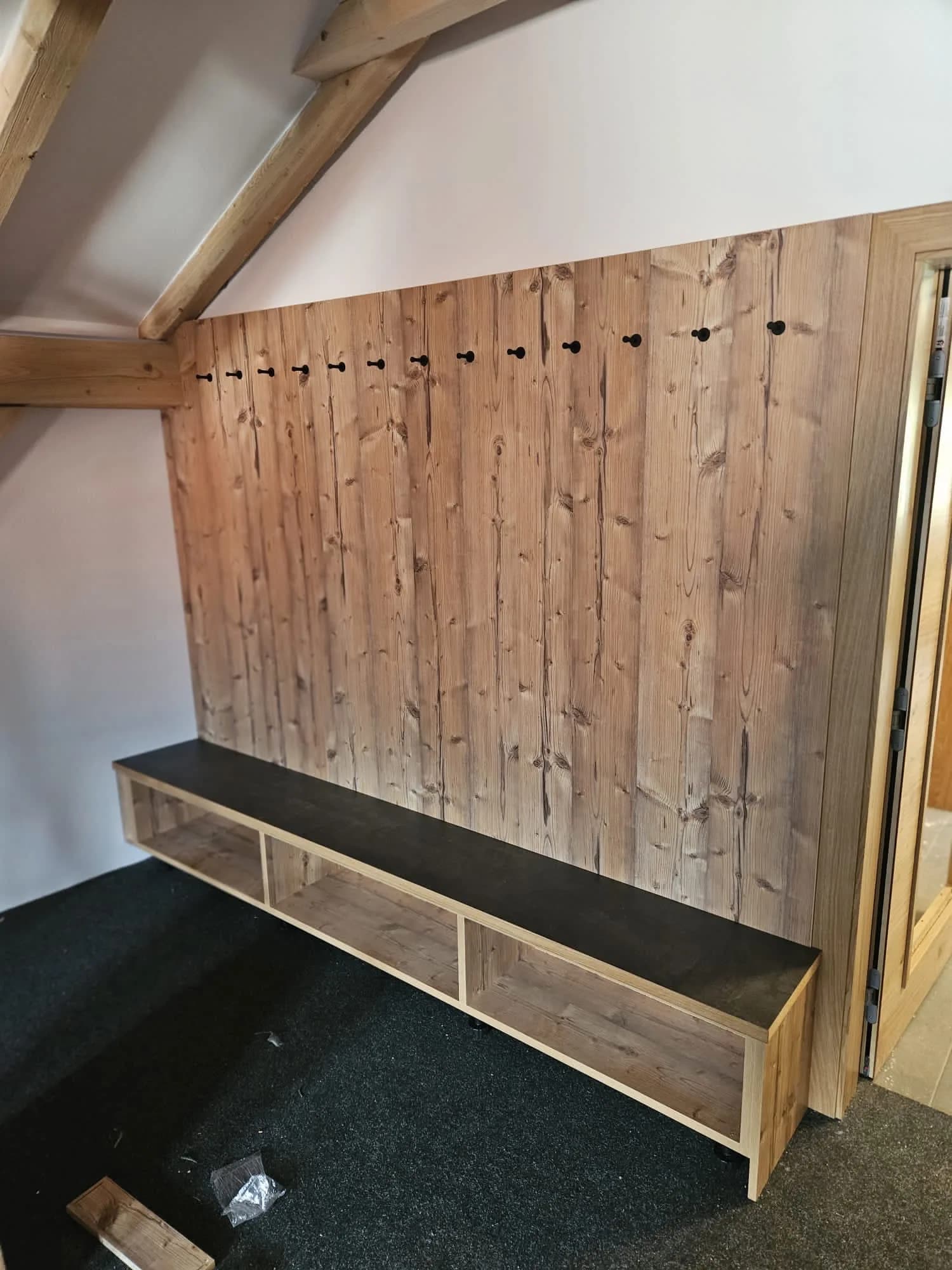 Eingebaute Sitzbank mit Garderobenhaken aus Holz in einem Eingangsbereich