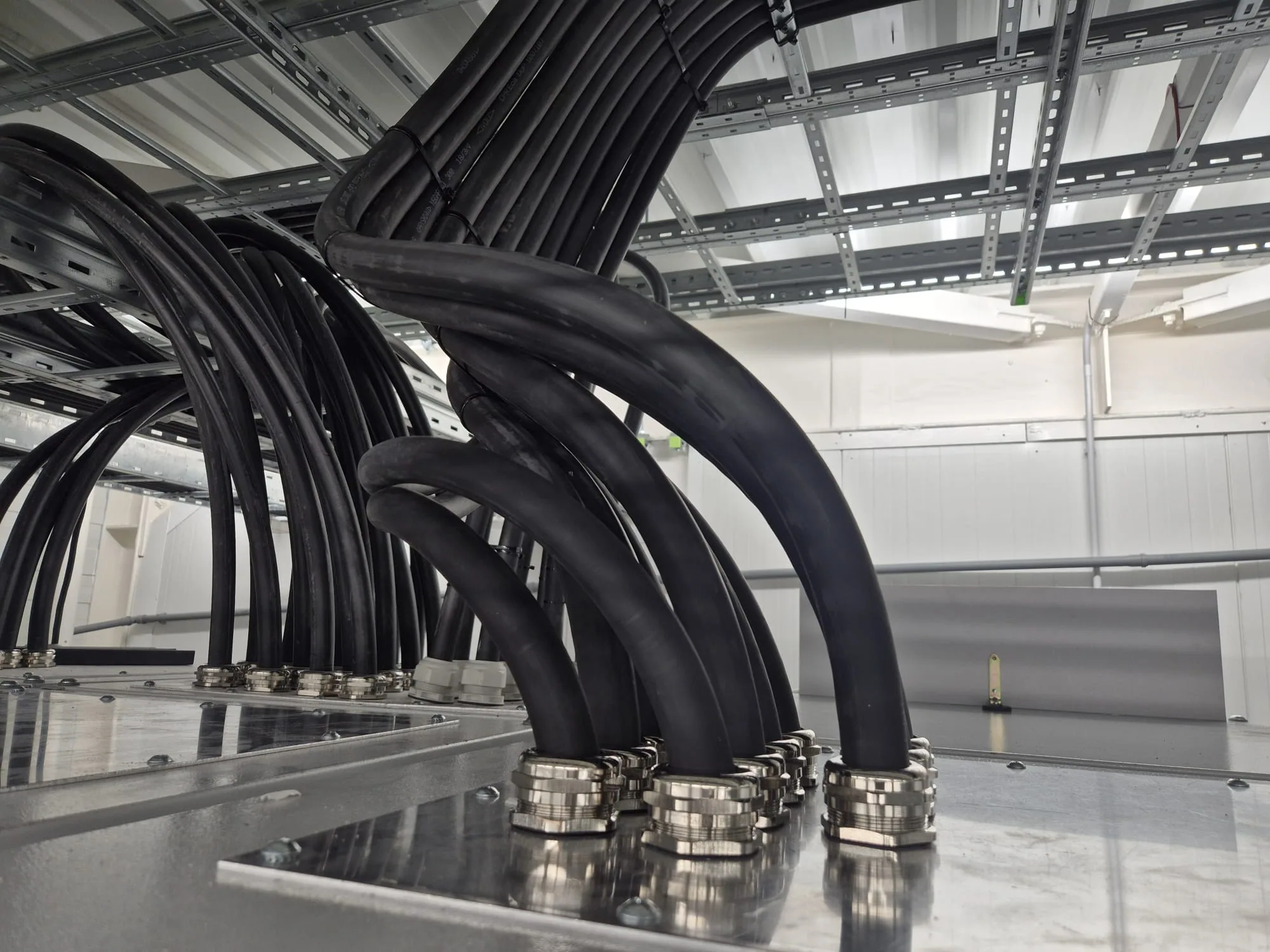 Techniker auf Hubarbeitsbühnen verlegen Kabeltrassen unter der Decke einer Industriehalle