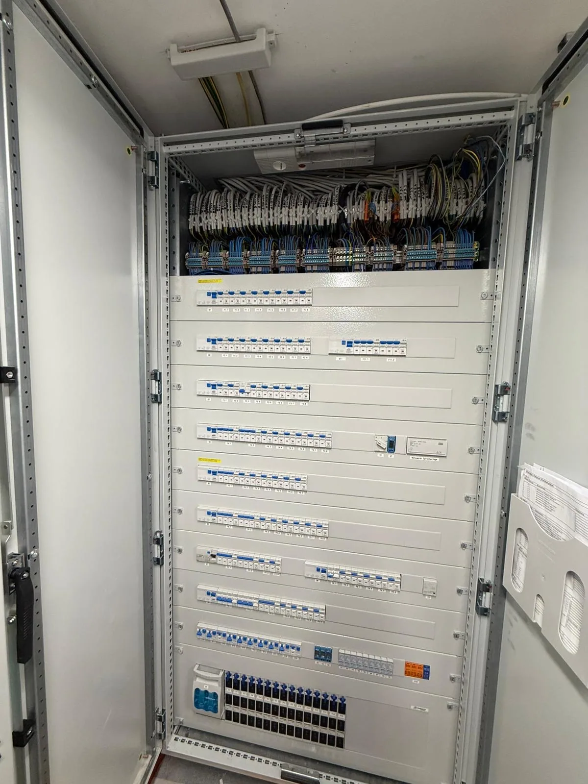 Vollständig bestückter Verteilerschrank mit geöffneten Türen in einem Technikraum