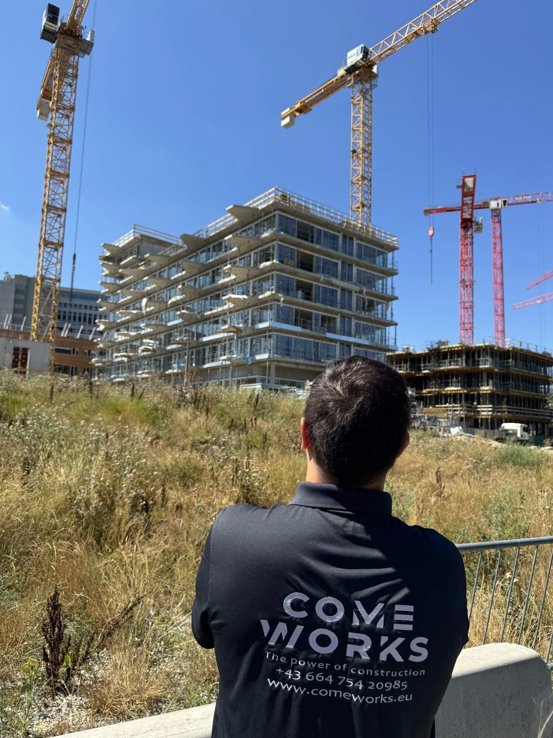 COME WORKS Mitarbeiter blickt auf eine Baustelle mit mehreren Baukränen