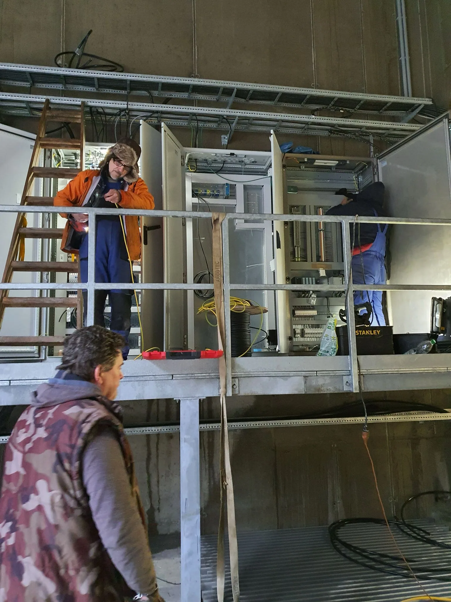 Elektrotechniker in Schutzausrüstung öffnet einen Schaltschrank auf einer Baustelle