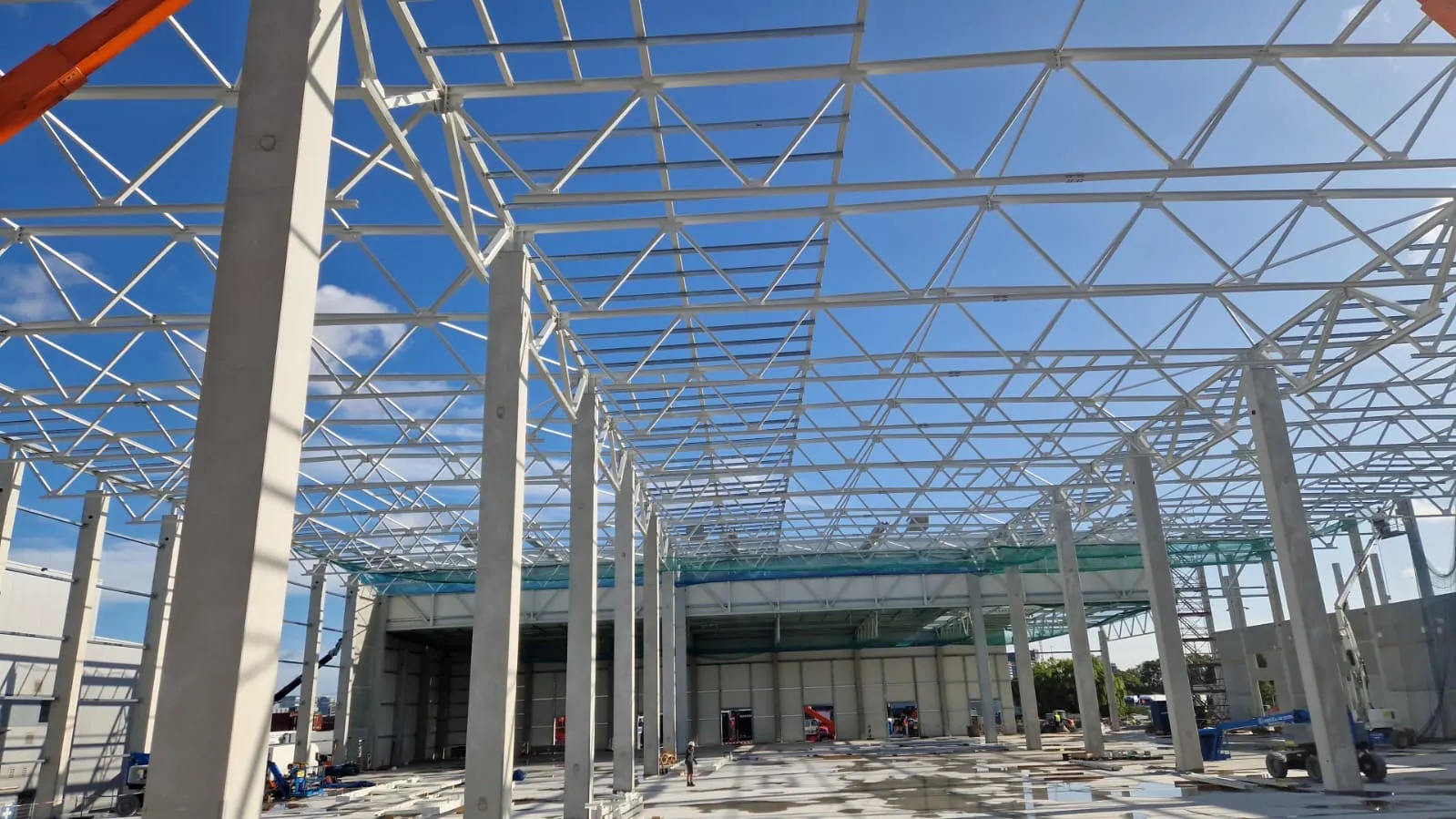 Stahlfachwerk einer Industriehalle im Rohbau unter blauem Himmel